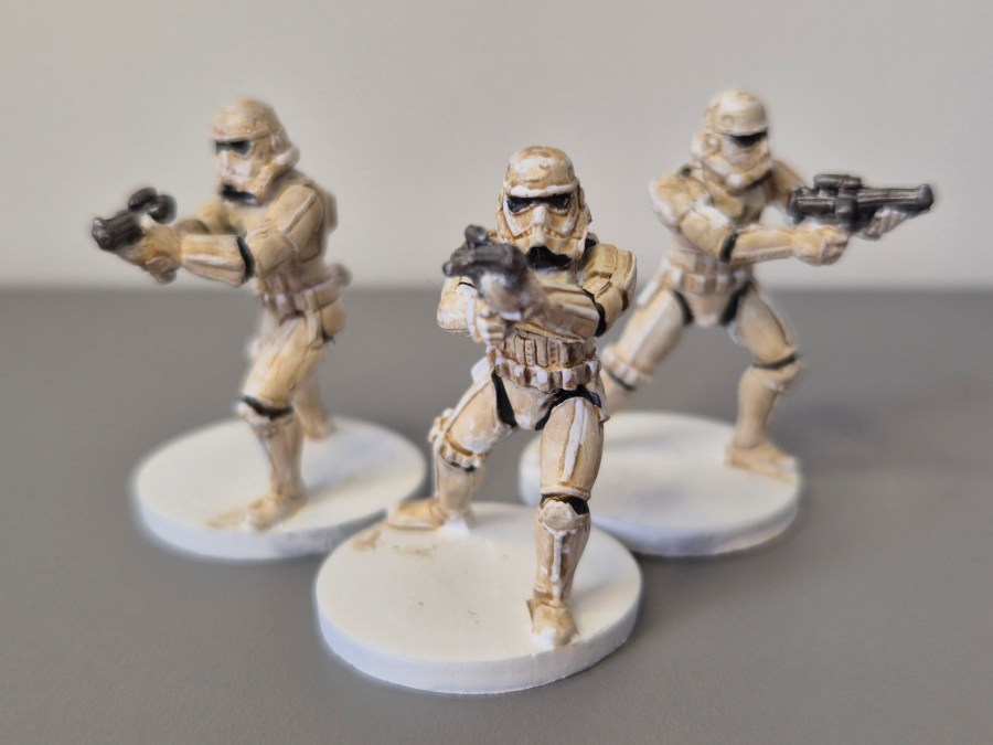 Tre figurine di soldati in armatura bianca con armi, pronte per l'azione.